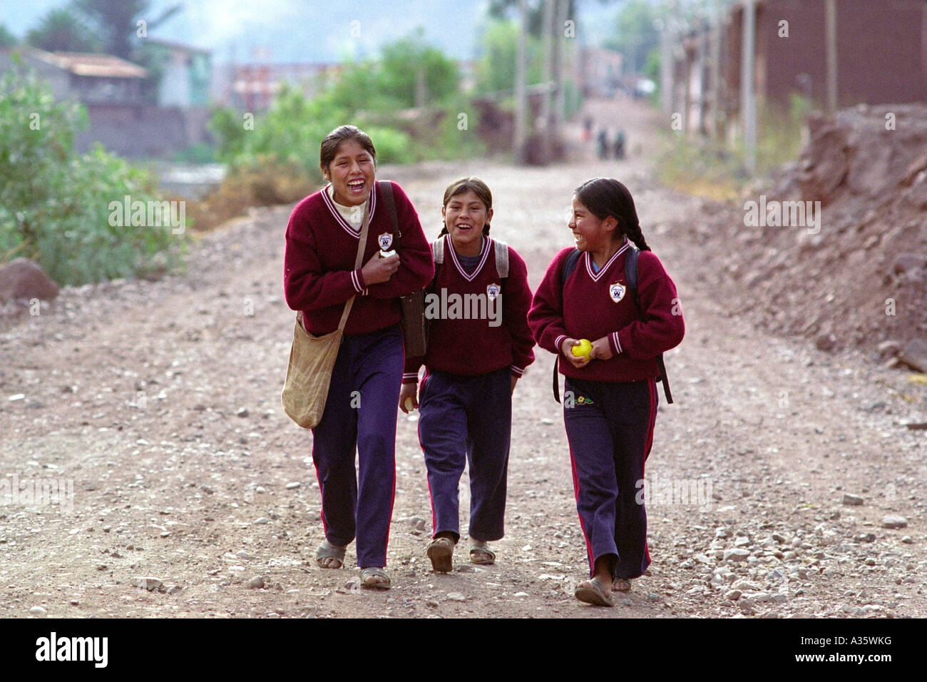 Three girls dressed in school uniforms walk laughing down the street in