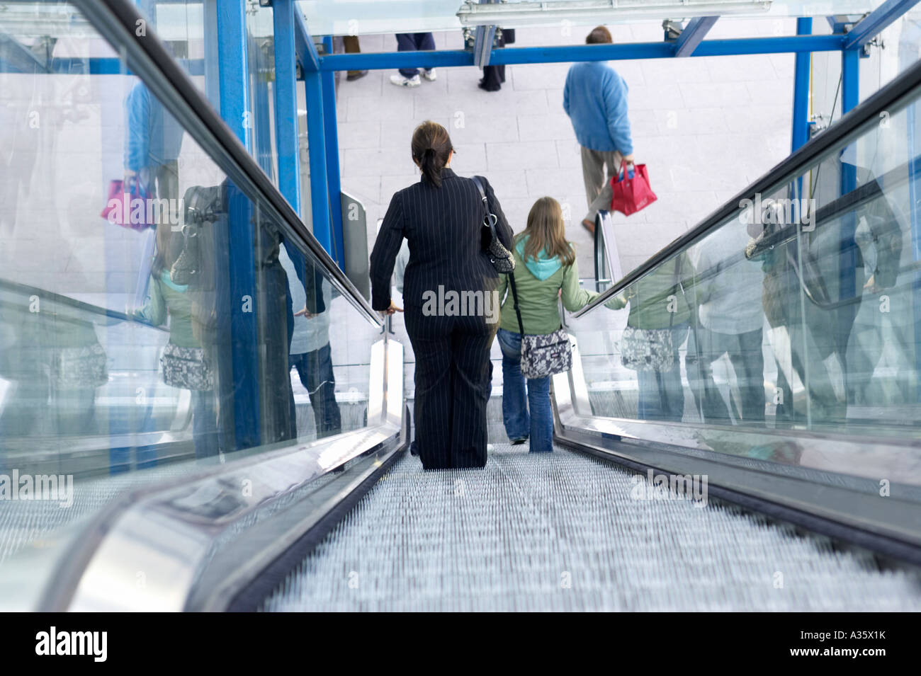 young woman in pinstripe business suit goes down escalator at connolly station dublin Stock Photo