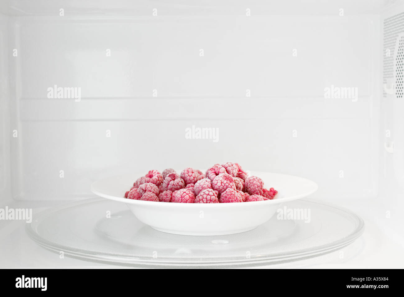 Plate Of Frozen Raspberries In Microwave Oven Stock Photo