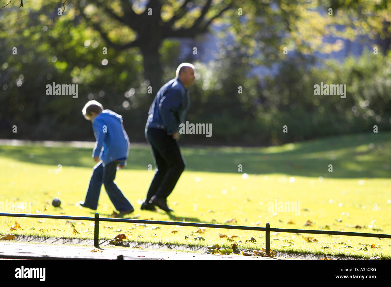 father and son play football in the grass in st Stephens Green Dublin