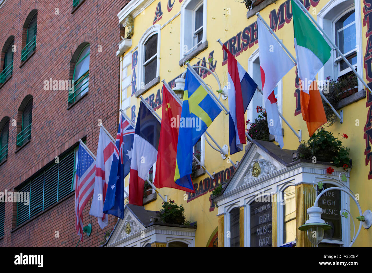 multinational flags hanging outside traditional irish bar in temple bar dublin next to modern red brick building Stock Photo
