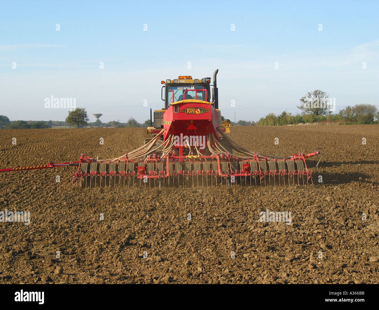 Seed drill, tractor sowing seed for crops, agricultural farming machinery Drilling the field, Norfolk, England, United Kingdom Stock Photo