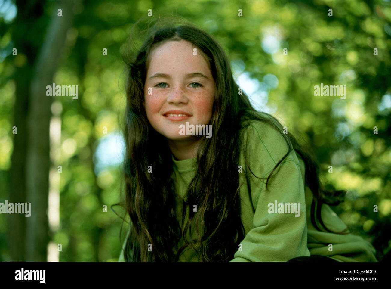 A beautiful girl with long brown hair and wearing a green shirt is ...