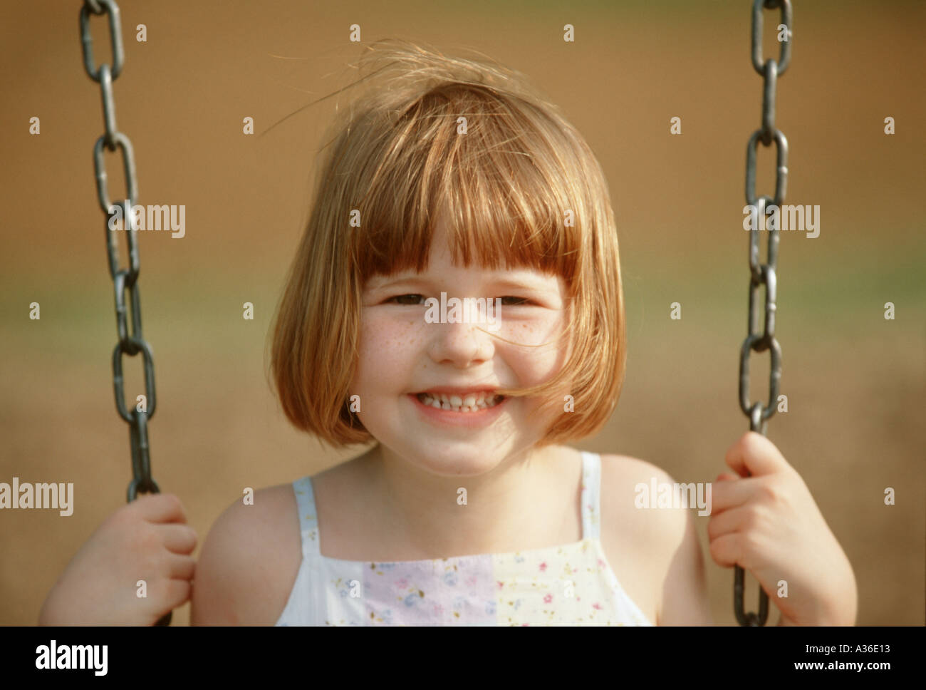 A Cute Young Girl With Strawberry Blonde Hair Sits In A Swing And