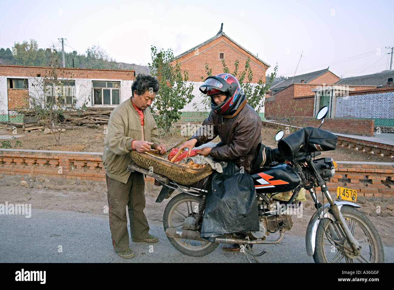 CHINA SIMATAI Motorcycle delivery man selling bread to farmer Stock Photo