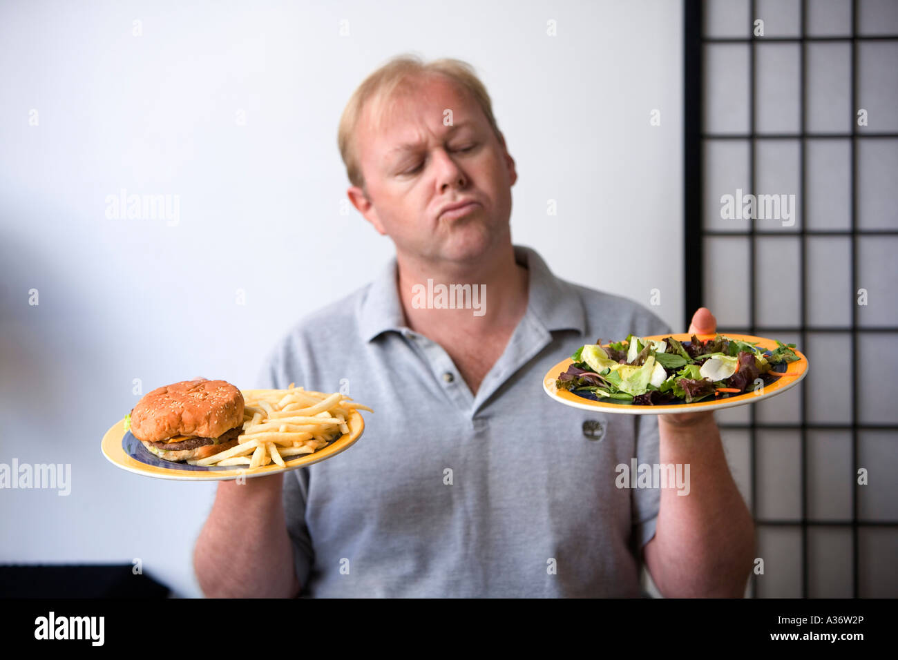 Man chooses between salad and burger with chips Stock Photo