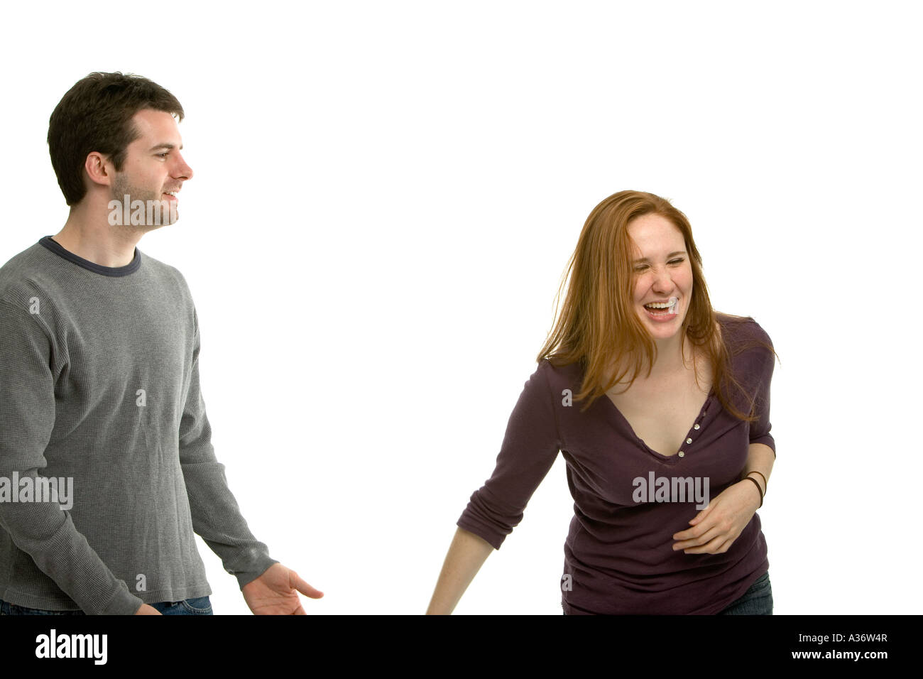 Attractive young man says something funny that makes his red haired girlfriend laugh Stock Photo