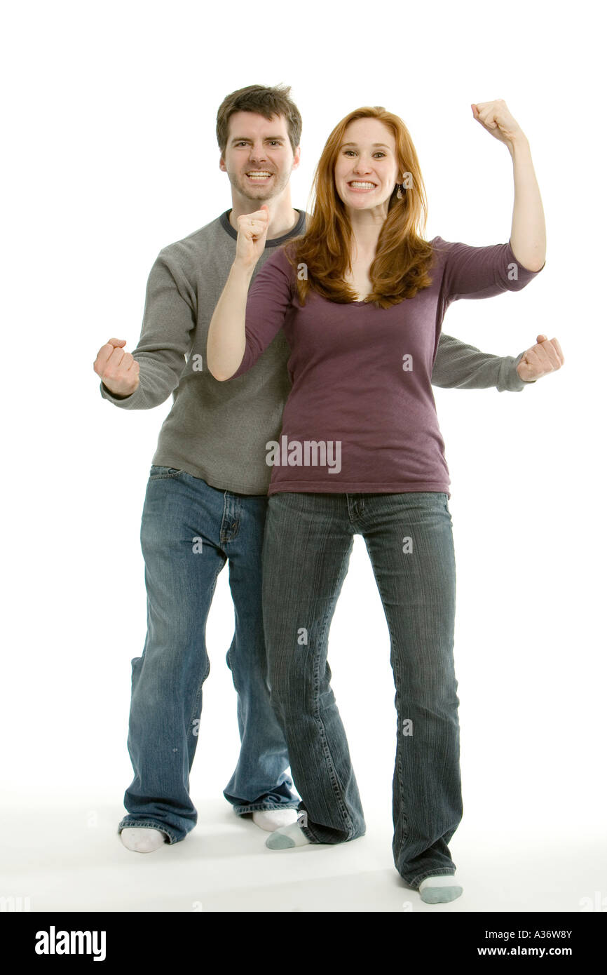 An attractive young couple gleefully celebrate some good news punching ...