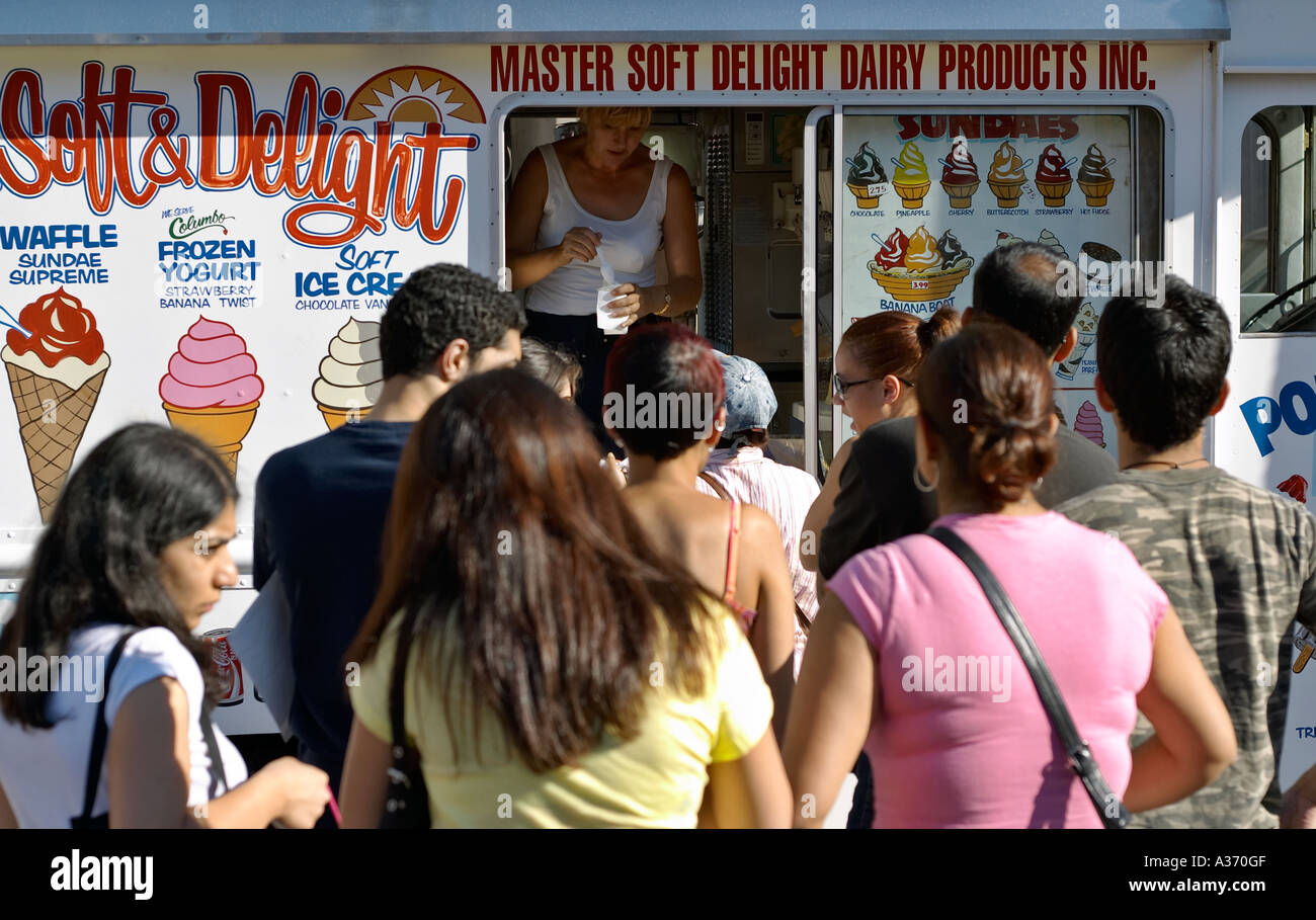 People waiting in line to buy ice cream on a hot summer day. Focus is on the ice cream truck and the sales lady. Stock Photo