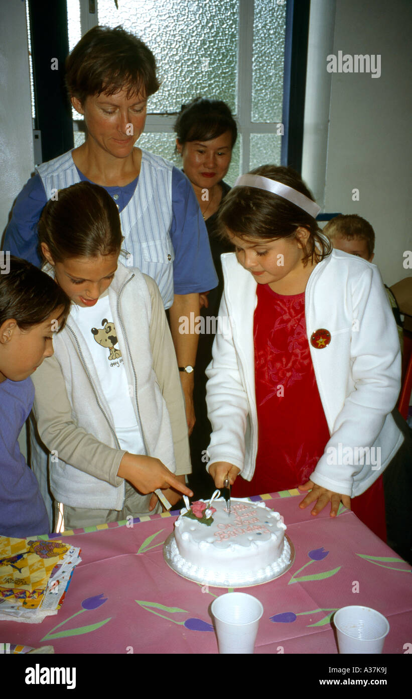 Birthday Party Nine Year Old Cutting Cake with Knife with Adult Present Stock Photo