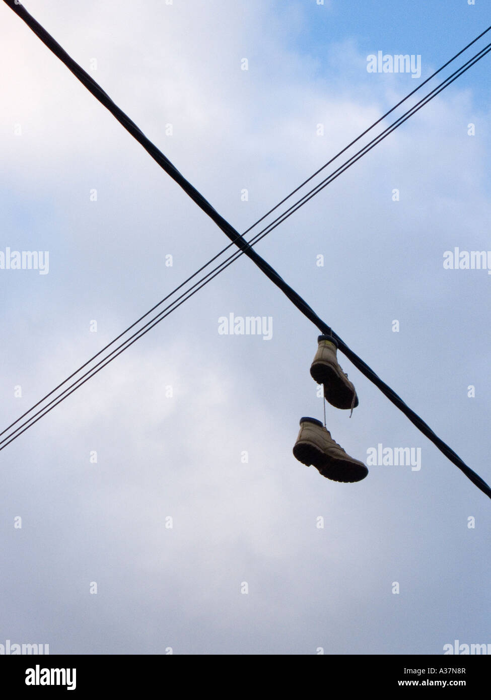 Boots hanging on a telephone wire tied together by shoe laces Stock Photo