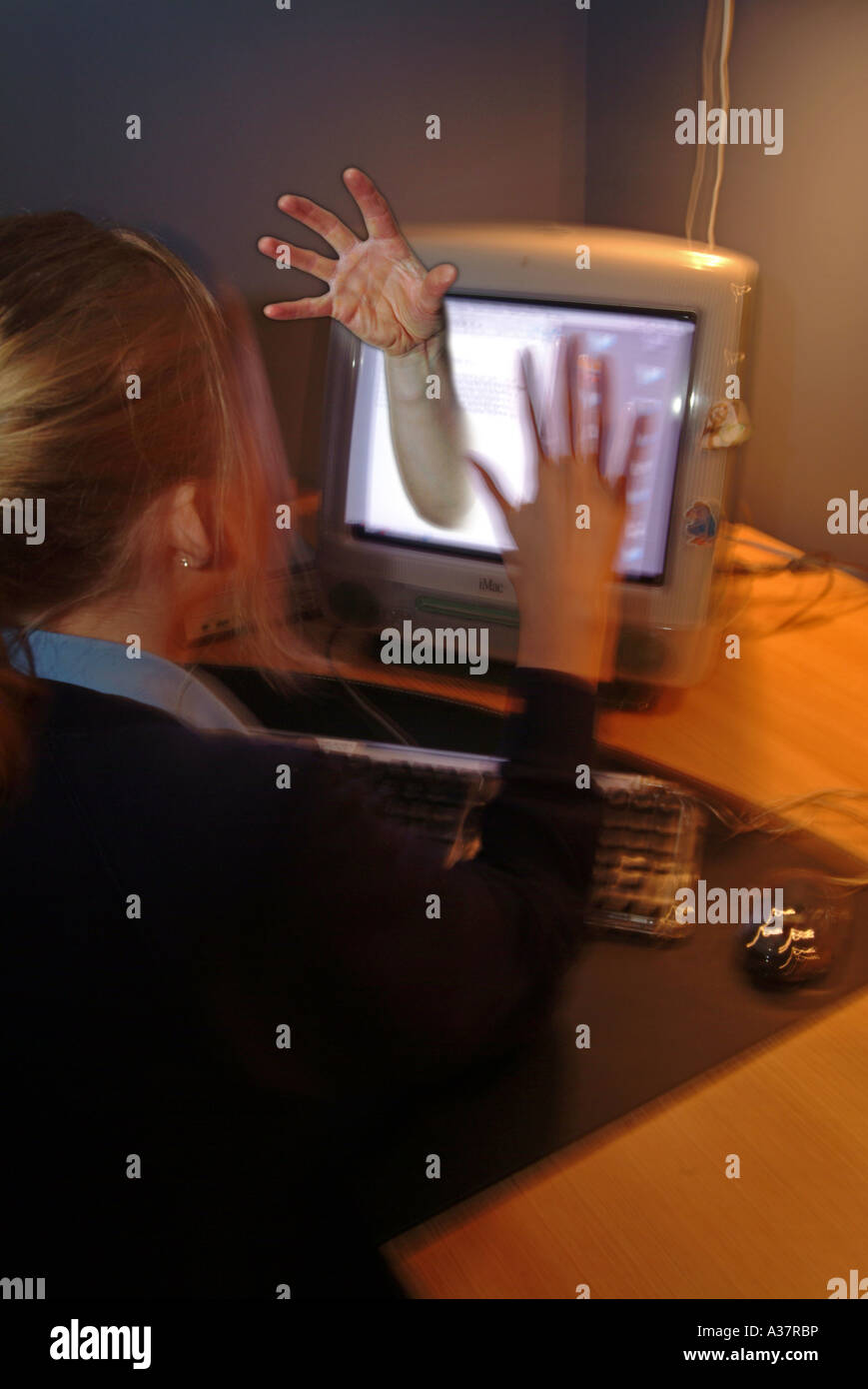 Young girl on a computer with a hand coming out from the screen as if she unable to escape  bullying even when at home UK Stock Photo