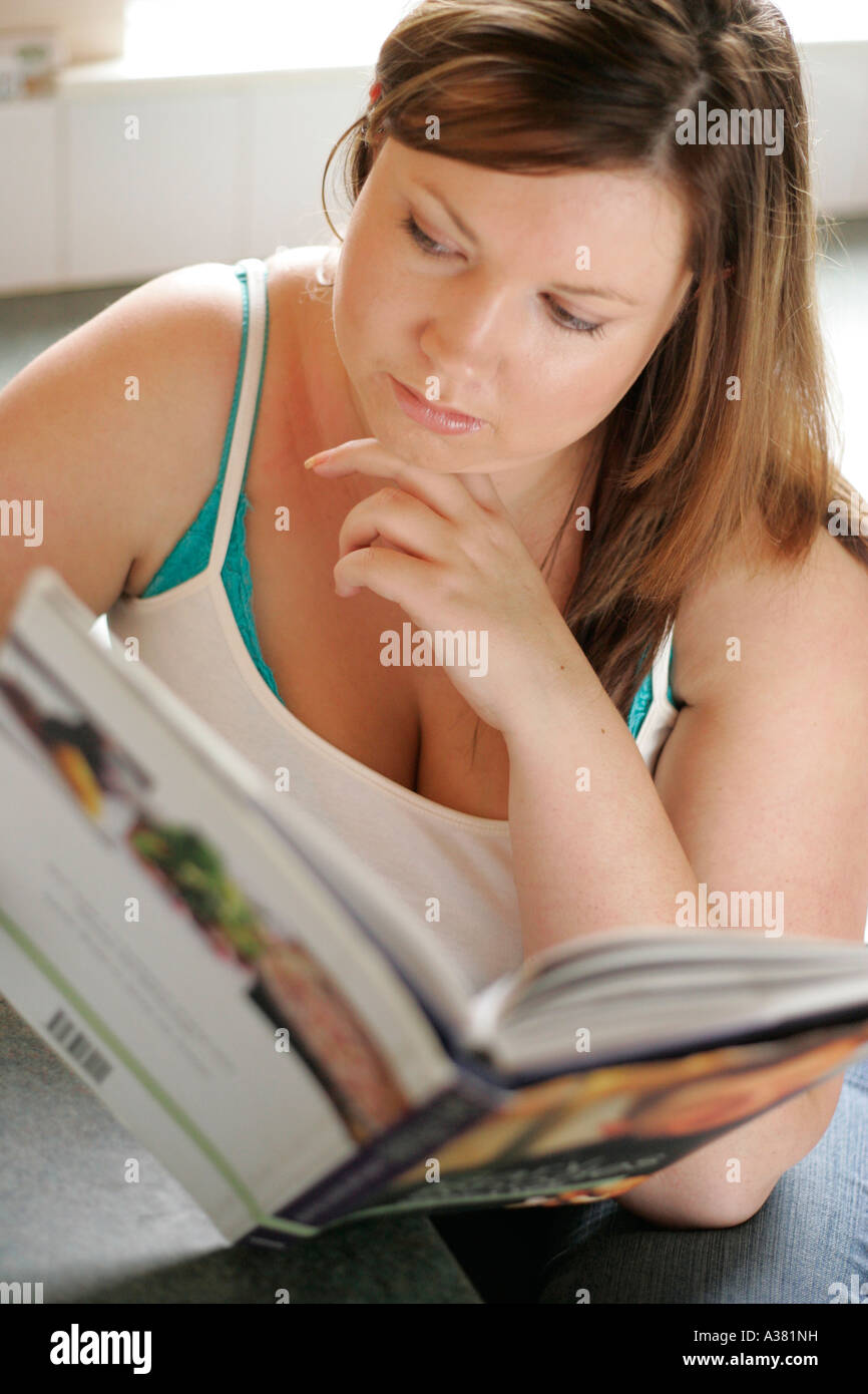plump woman reading cookery book Stock Photo