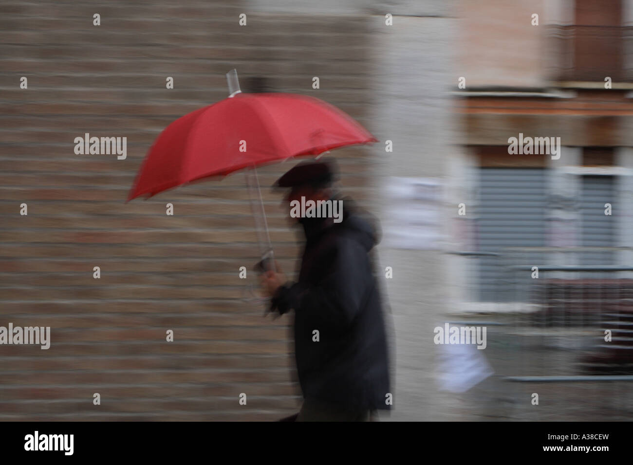 Man with a campo with colourful umbrella and boots in Venice, Italy