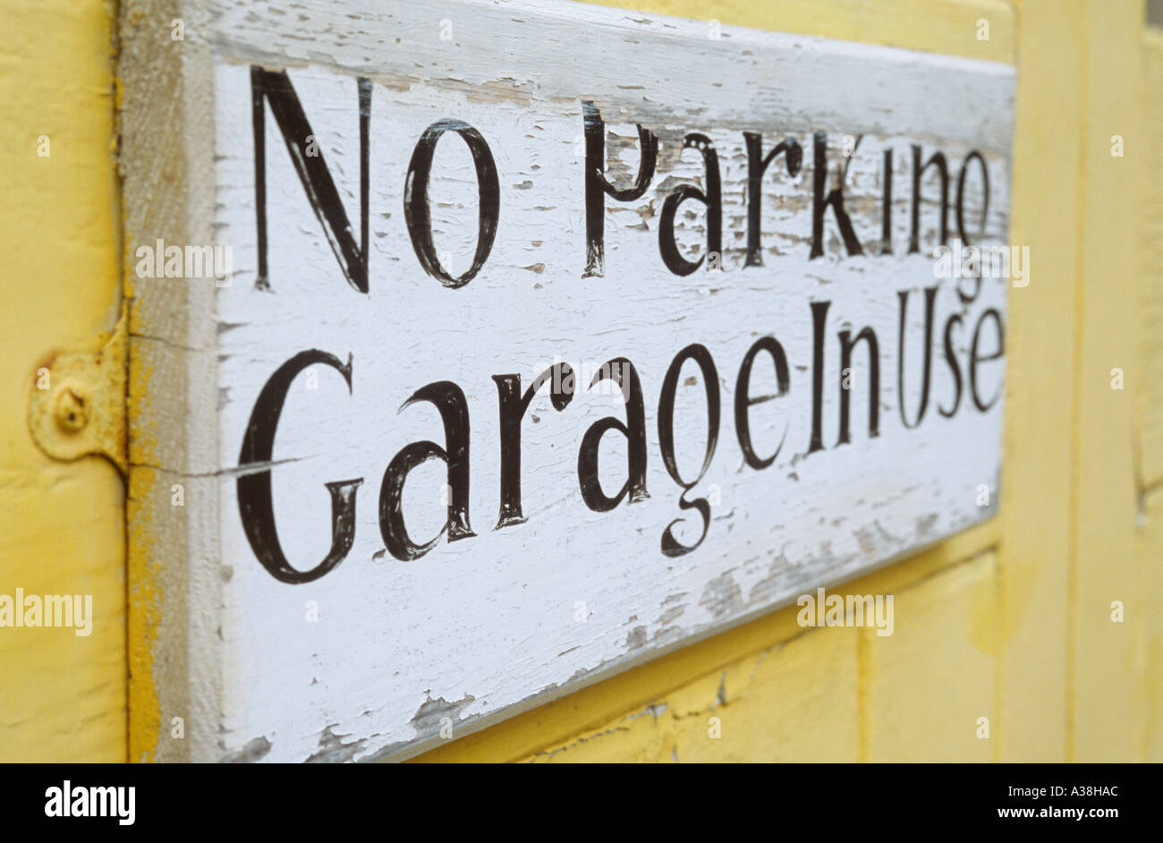 Stylish handpainted notice on yellow door or wall proclaiming No parking Garage in use Stock Photo
