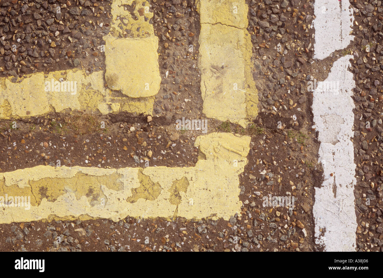 Close up view from above of worn out and patched up yellow and white parking restriction lines UK Stock Photo