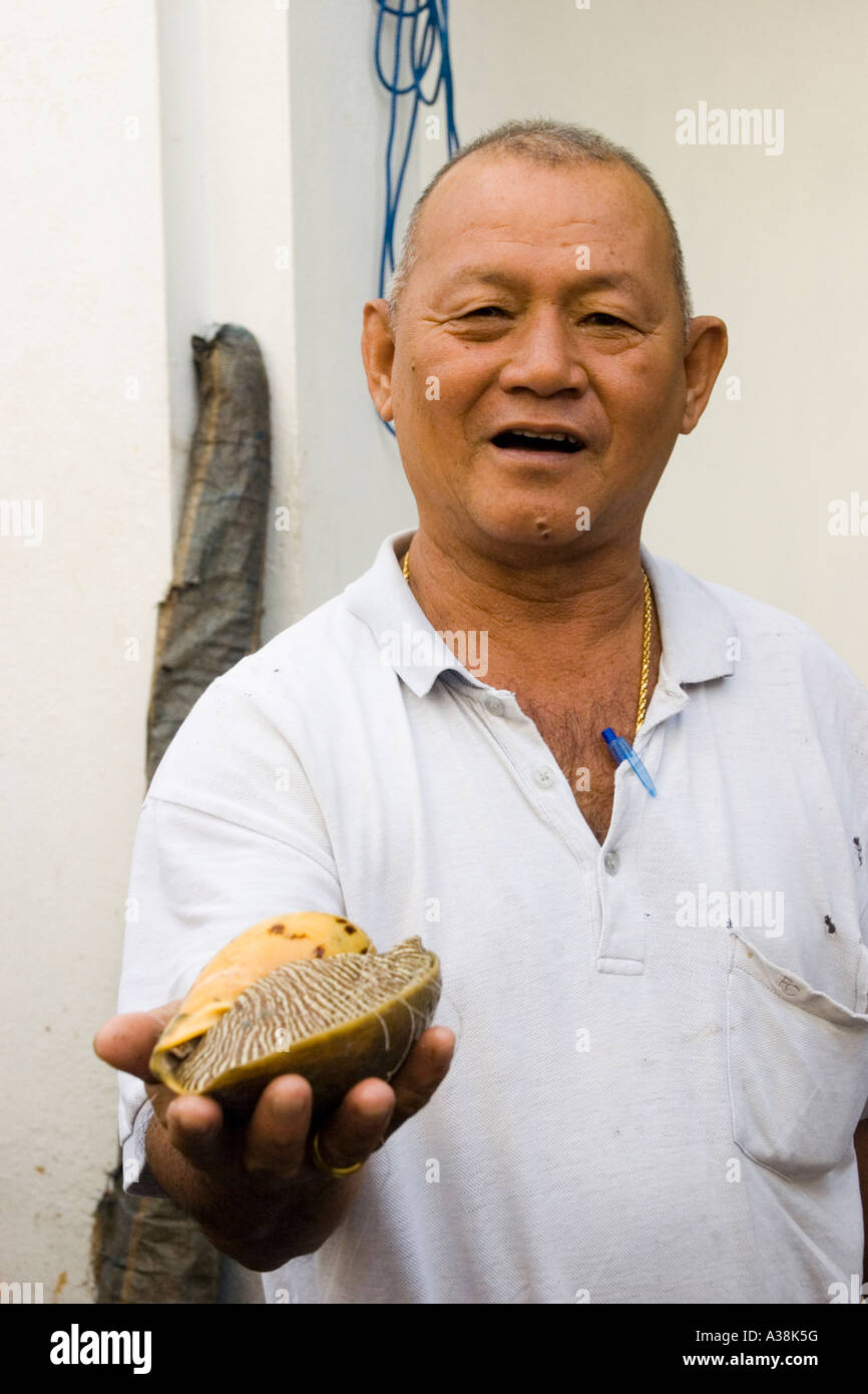 Merchant offers a live conch in the market Penang Stock Photo