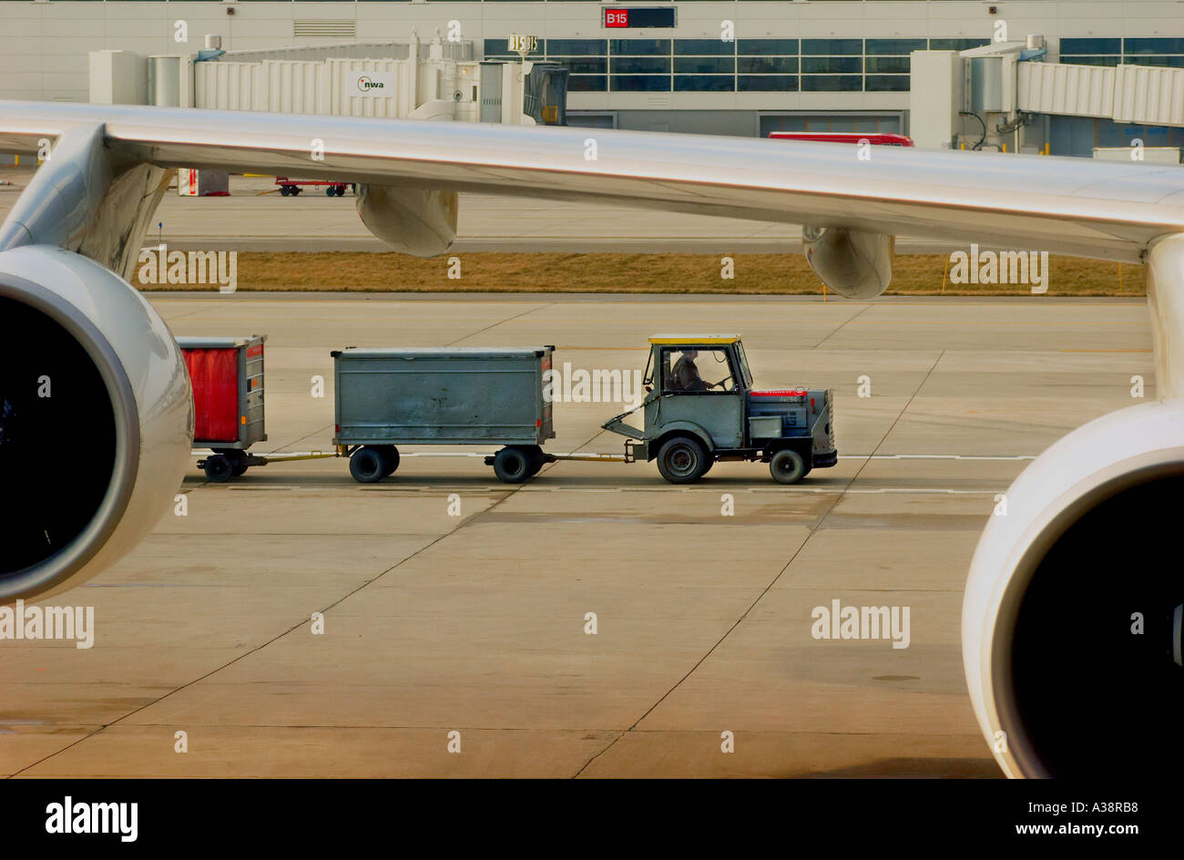 Airport baggage handler driving a baggage truck past an aircraft Stock Photo
