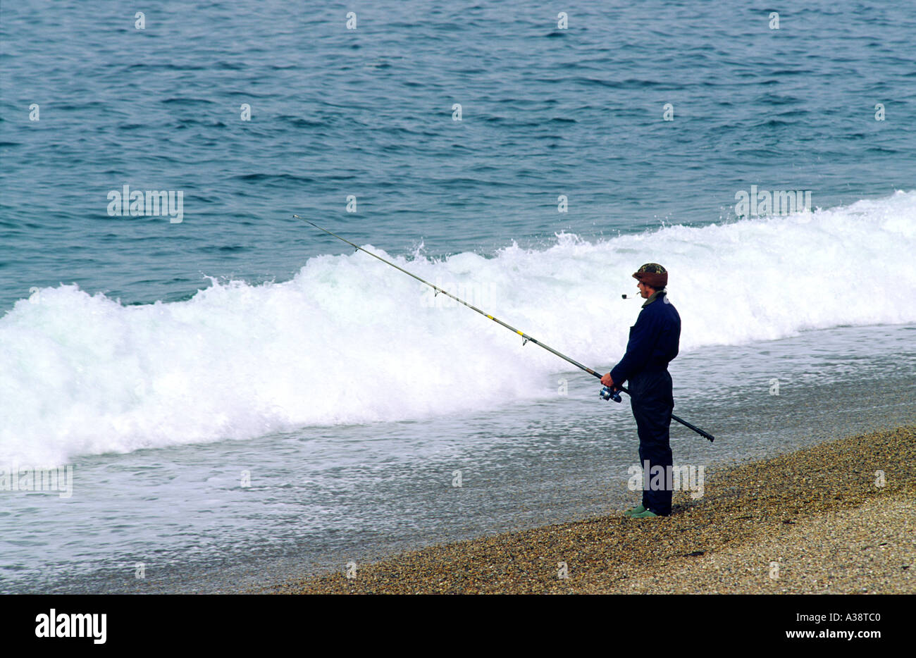 Fisherman shore fishing sea angling on Chesil Beach, Dorset on the