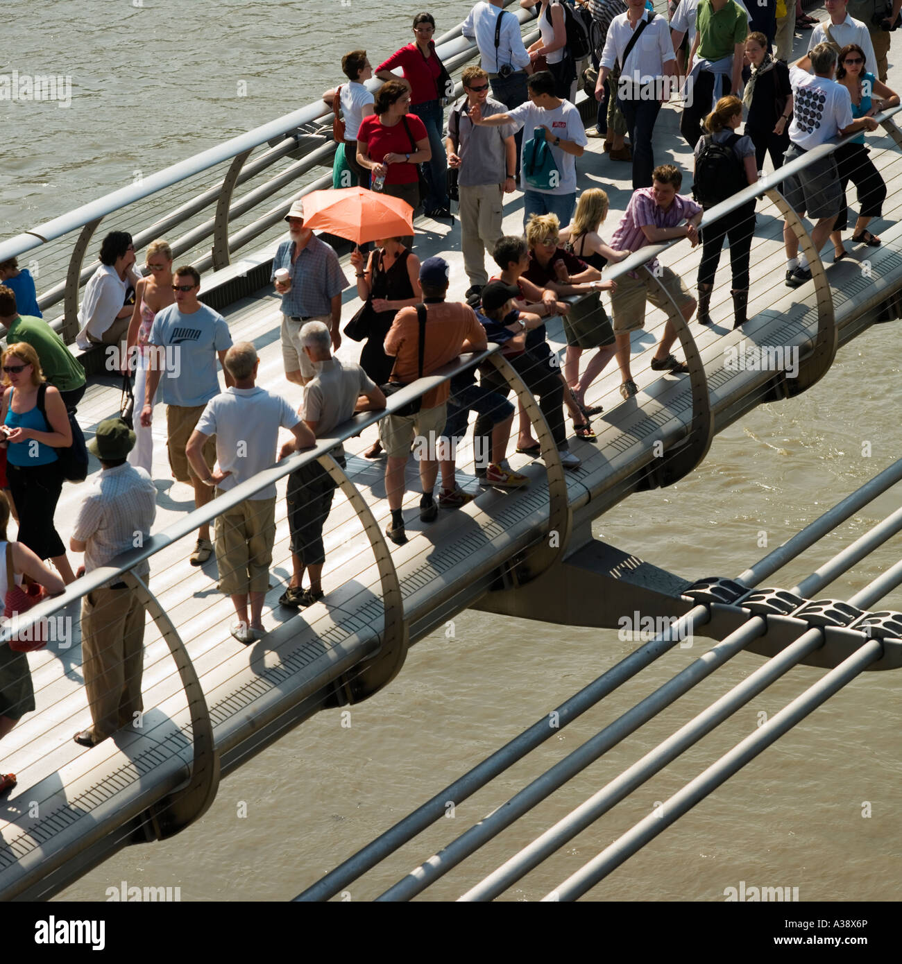 throng of people crossing Millennium Bridge over the River Thames London England UK Stock Photo