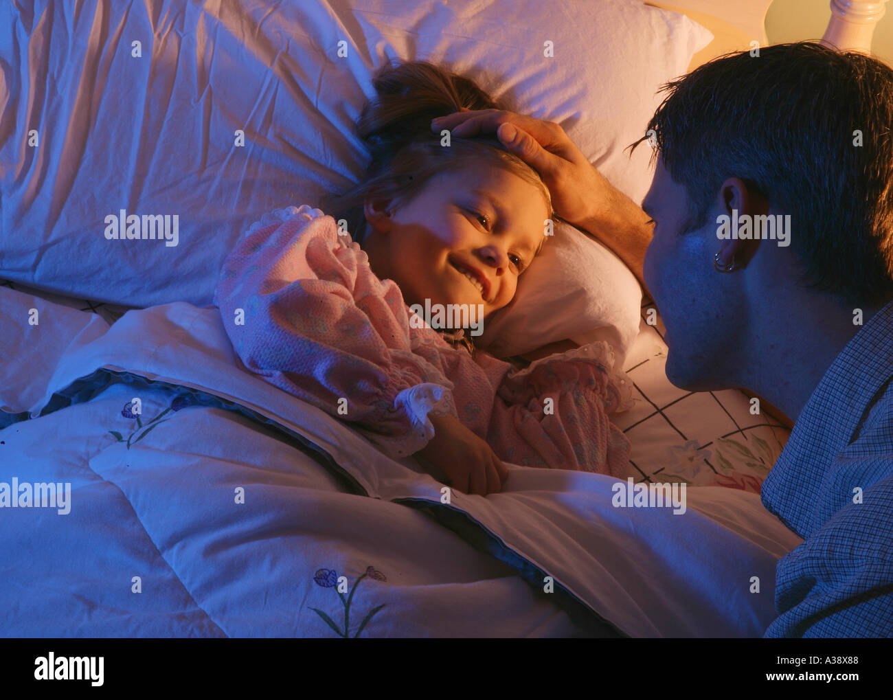 Father tucking daughter into bed Stock Photo Alamy