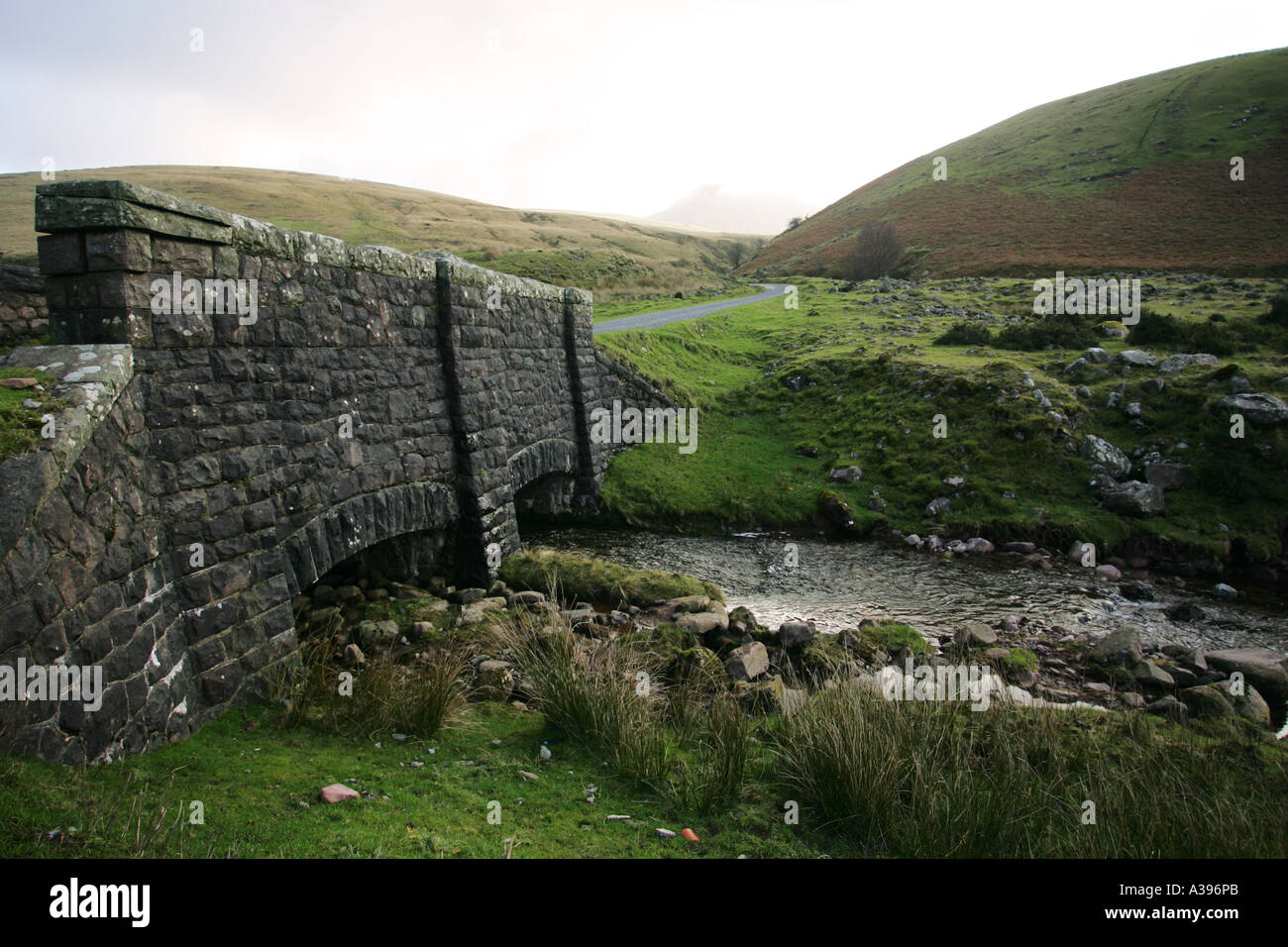 Ancient stone bridge and stream in lush green valley near Llyn y Fan Fach lake in Brecon beacons National Park Mid Wales UK Stock Photo