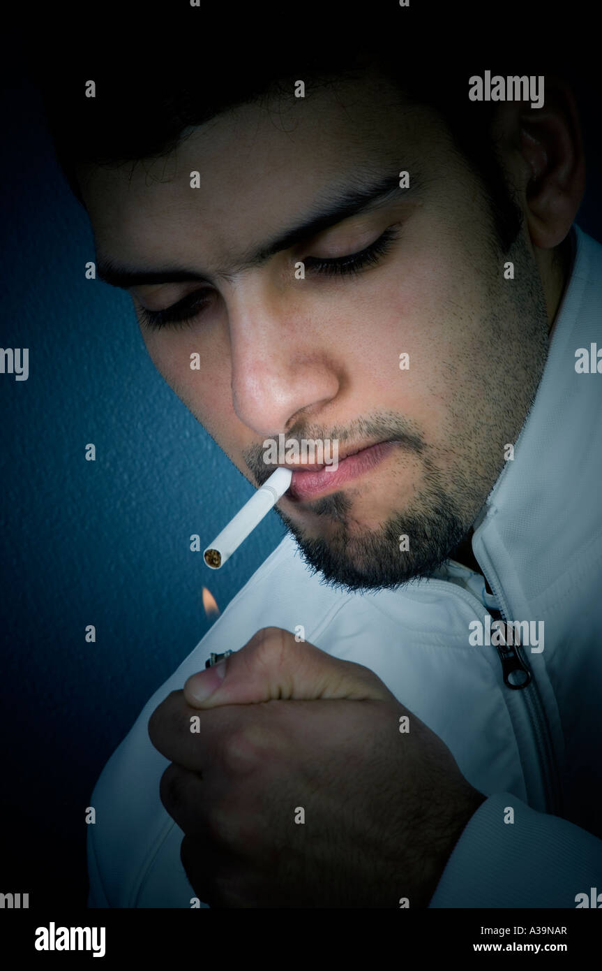 Young man Lighting a cigarette Indoors Stock Photo Alamy