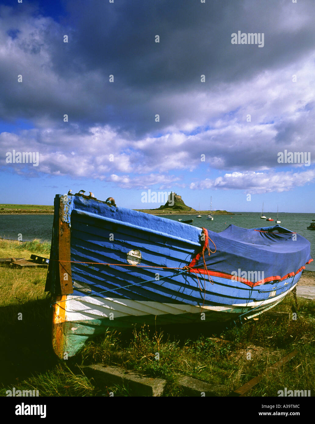 Wooden fishing boat on the shore at Holy Island with Lindisfarne Castle ...