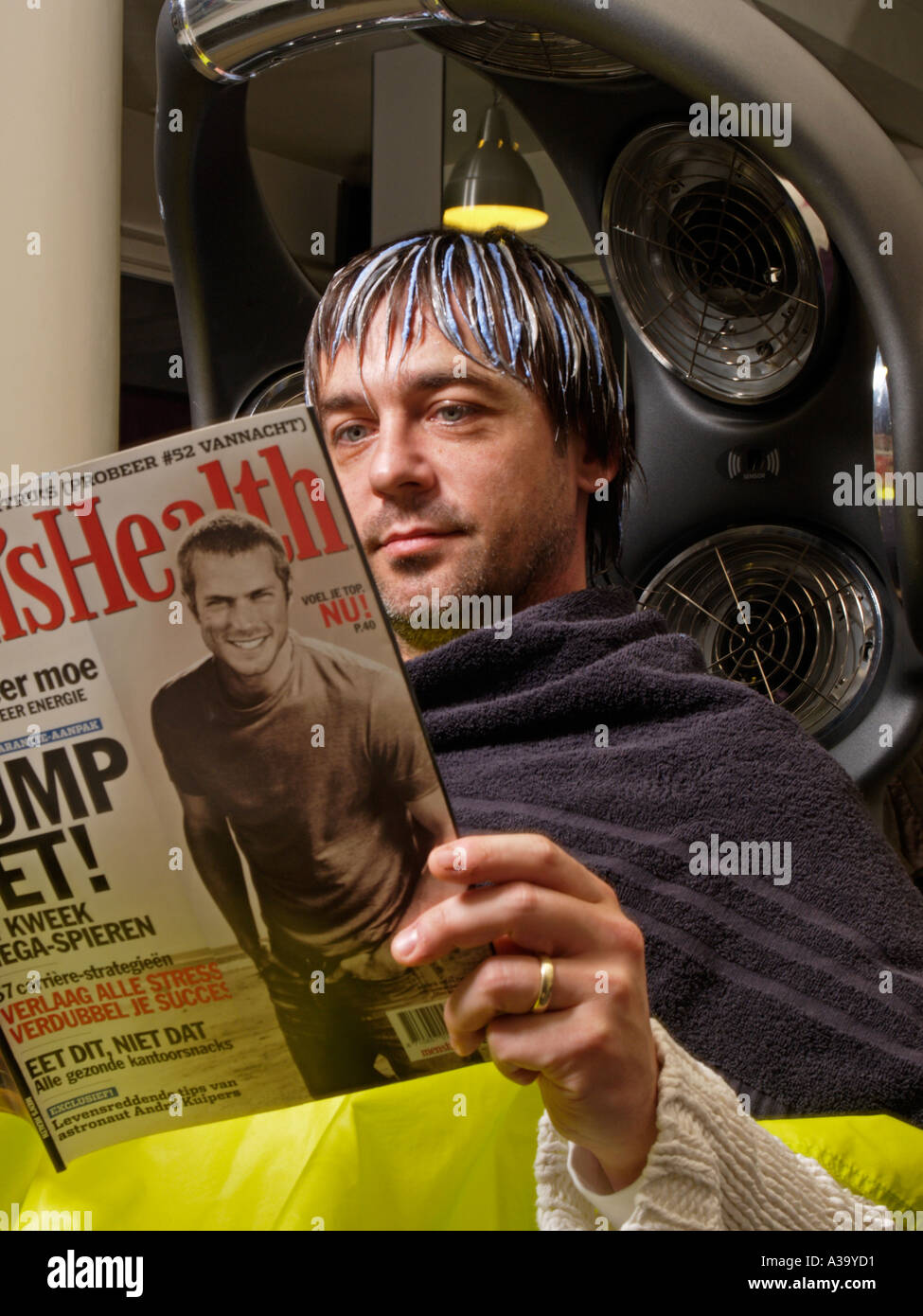 Man Reading Mens Health Magazine While Waiting Under A Hairdryer