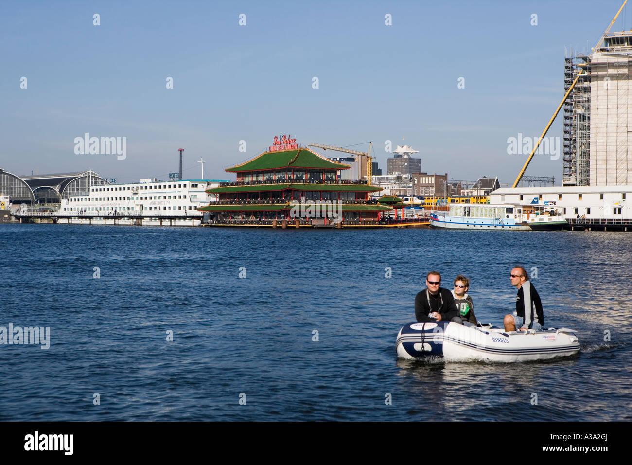 Rubber dinghy with floating Chinese restaurant in background, Amsterdam