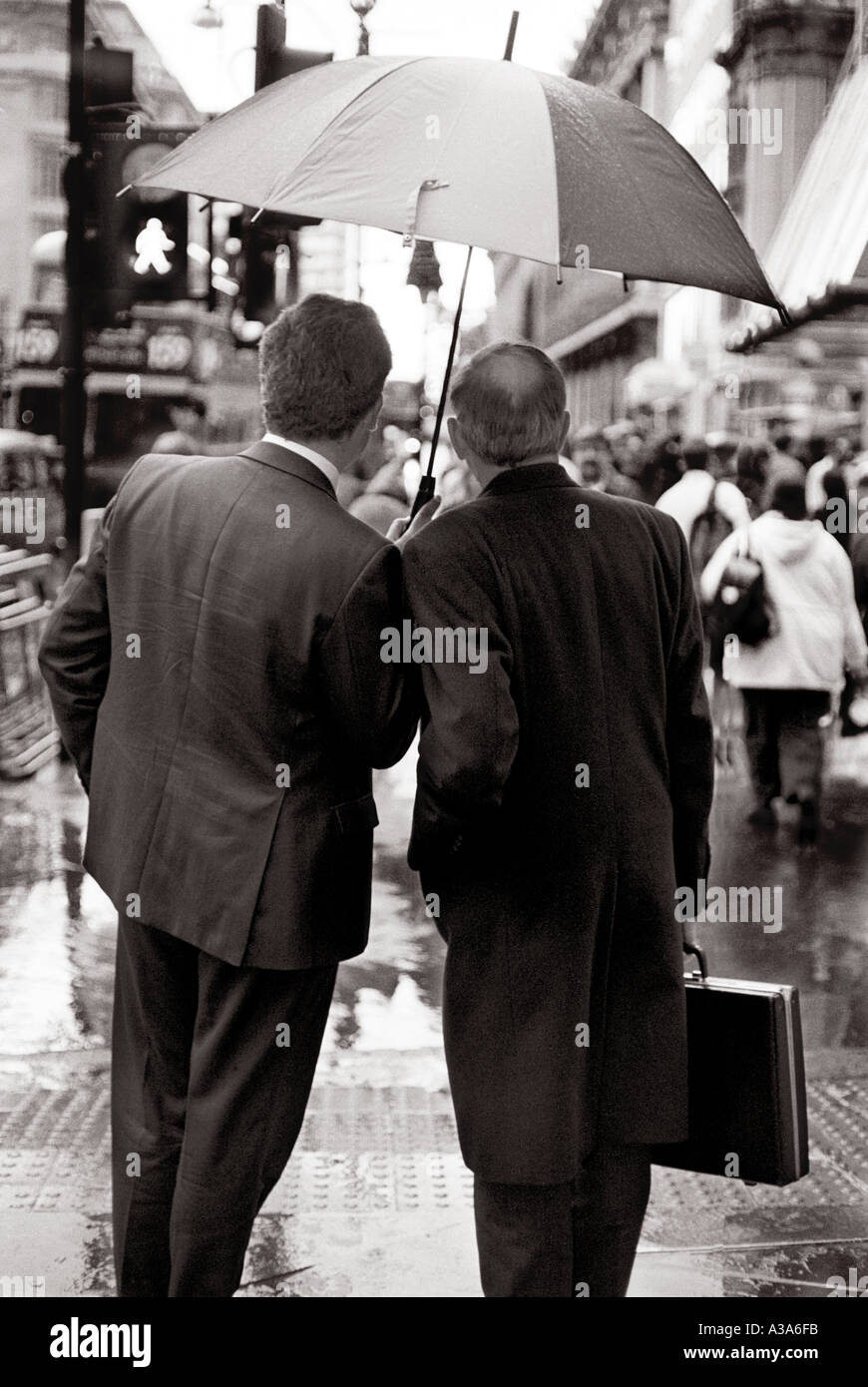 Two businessmen sharing  an umbrella, Oxford Street, London, UK. Stock Photo