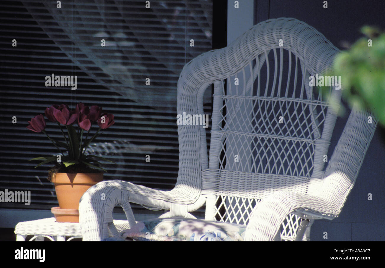 An Old Fashioned White Wicker Chair Sits On A Front Porch In