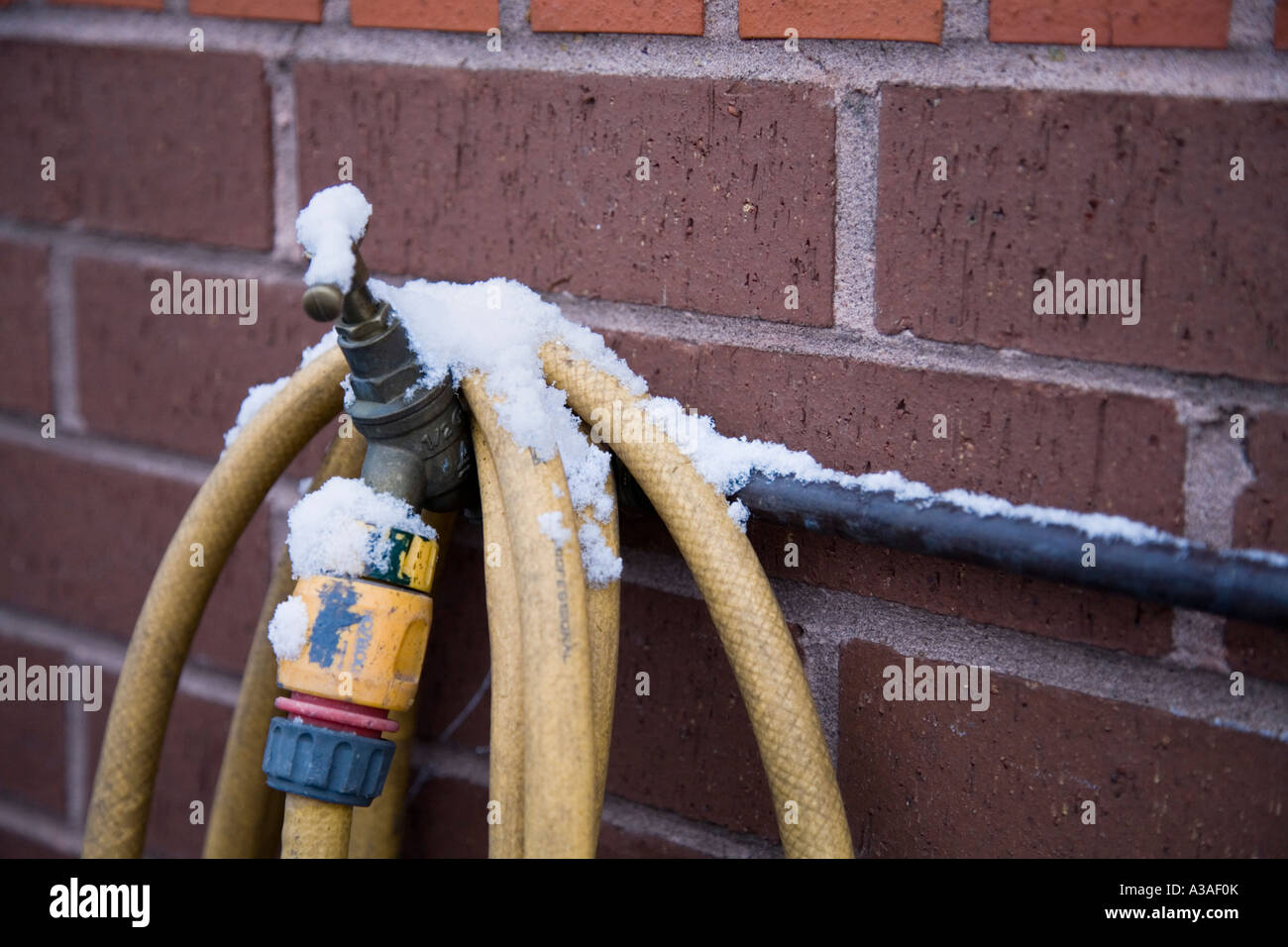 Outside tap and hose with snow UK Stock Photo