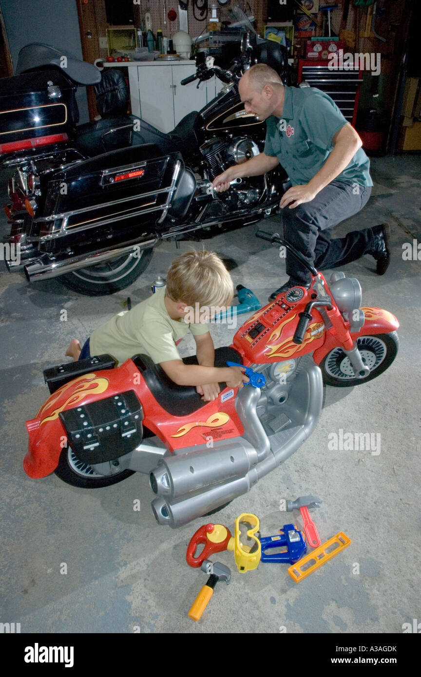 P33 102 5 yearold boy pretends to fix toy motorcycle as father fixes his real motorcyle in the
