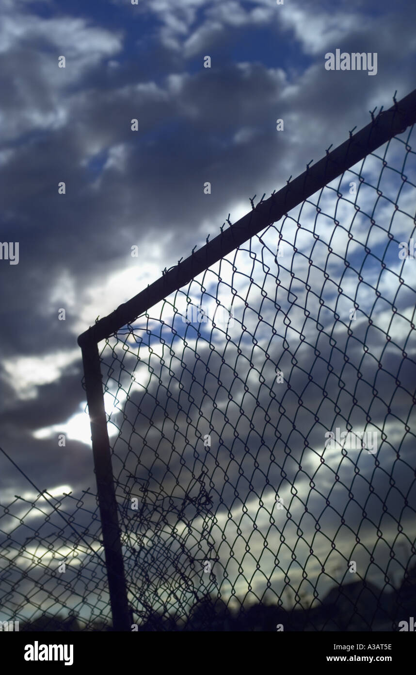 Gathering clouds behind chain link fence Stock Photo