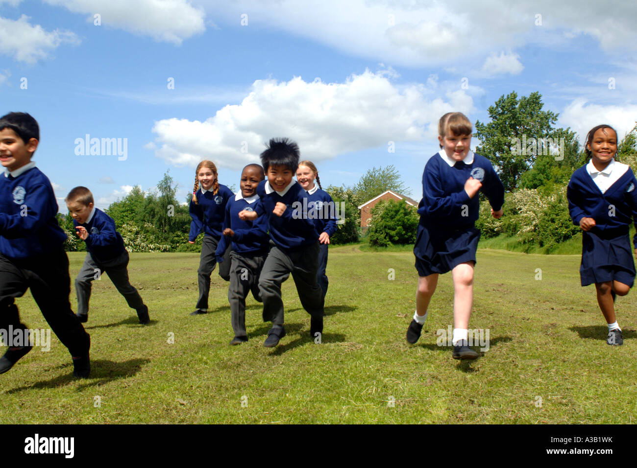 Mixed group of primary school children run on the school playing field Stock Photo