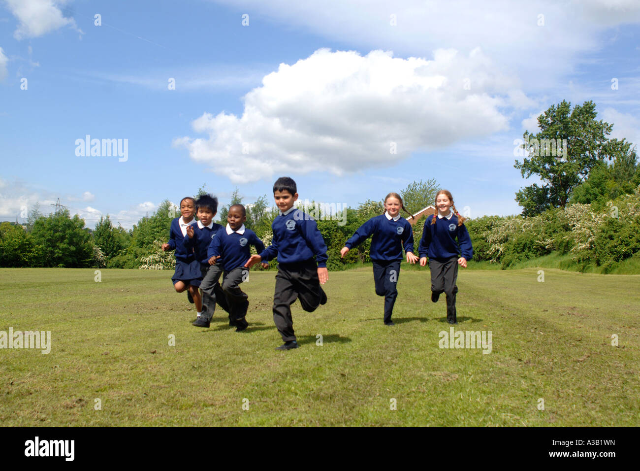 Mixed group of primary school children run on the school playing field Stock Photo