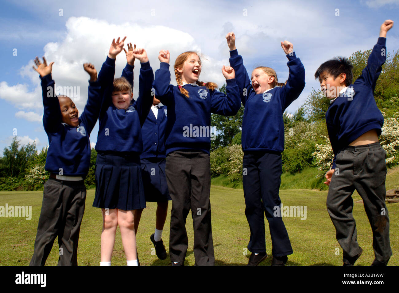 Mixed group of primary school children cheer their friends on the school playing field Stock Photo