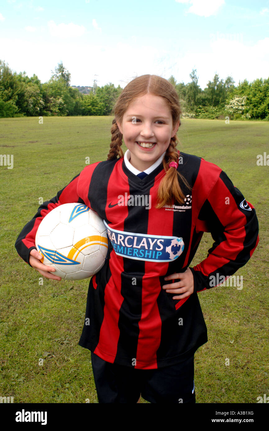 Girl holds a football on the school playing field West Yorkshire Stock Photo
