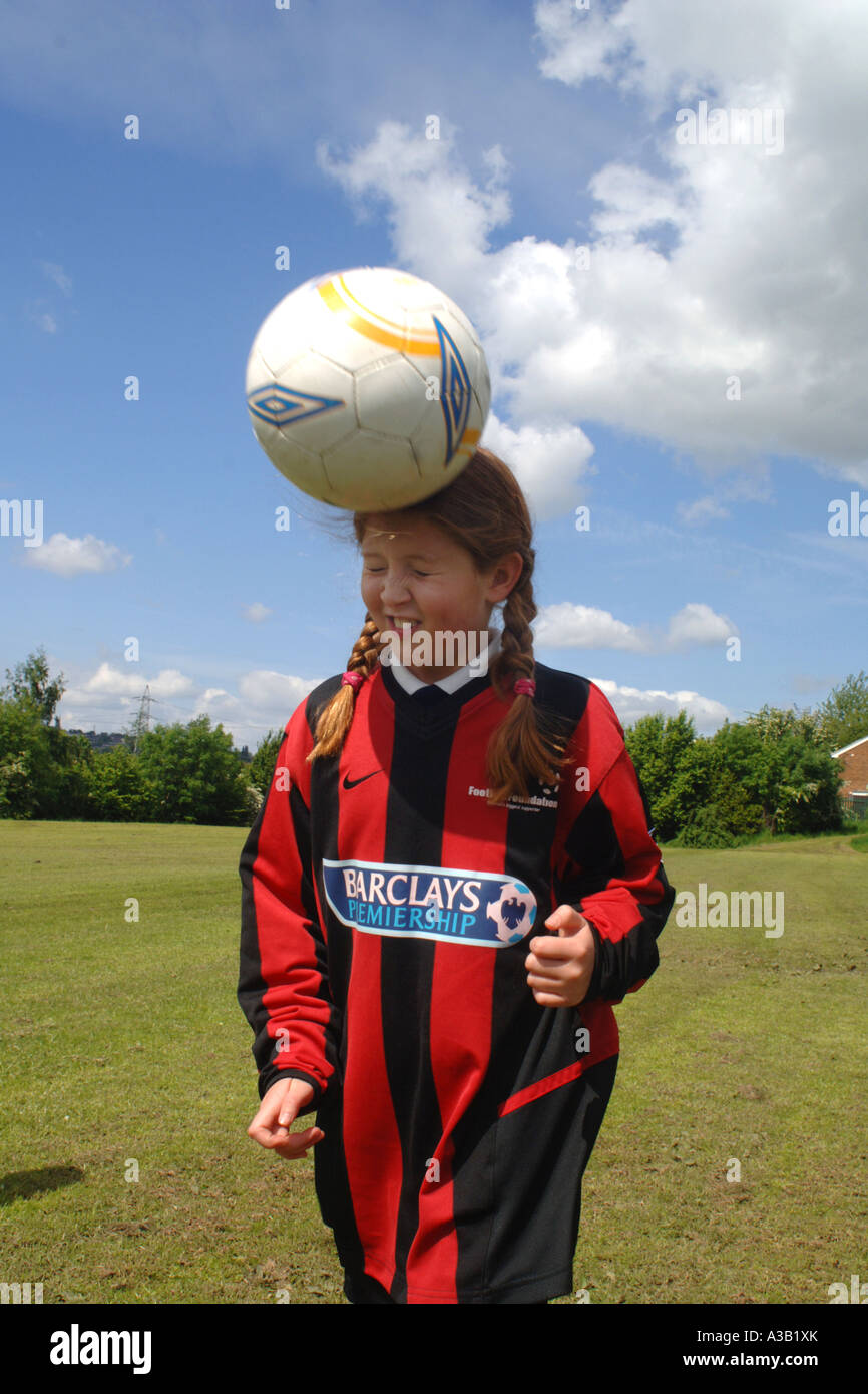 Girl heads a football on the school playing field West Yorkshire Stock Photo