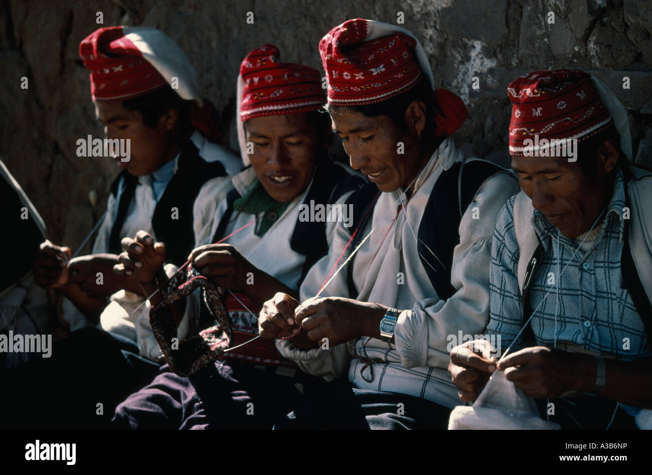 PERU South America Puno Lake Titicaca Taquile Island Line of men in traditional costume knitting Stock Photo