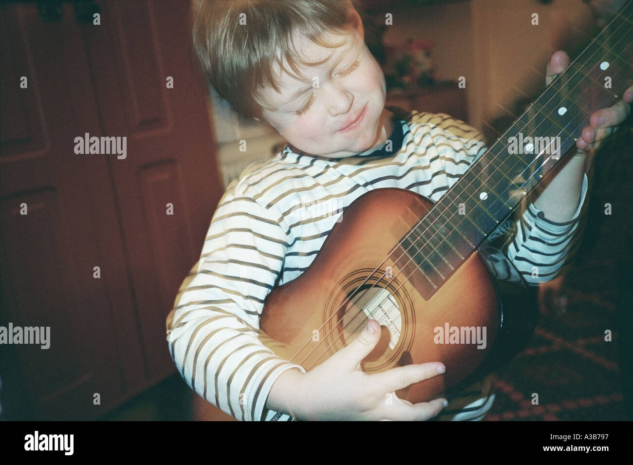 Five year old boy playing toy guitar Stock Photo - Alamy