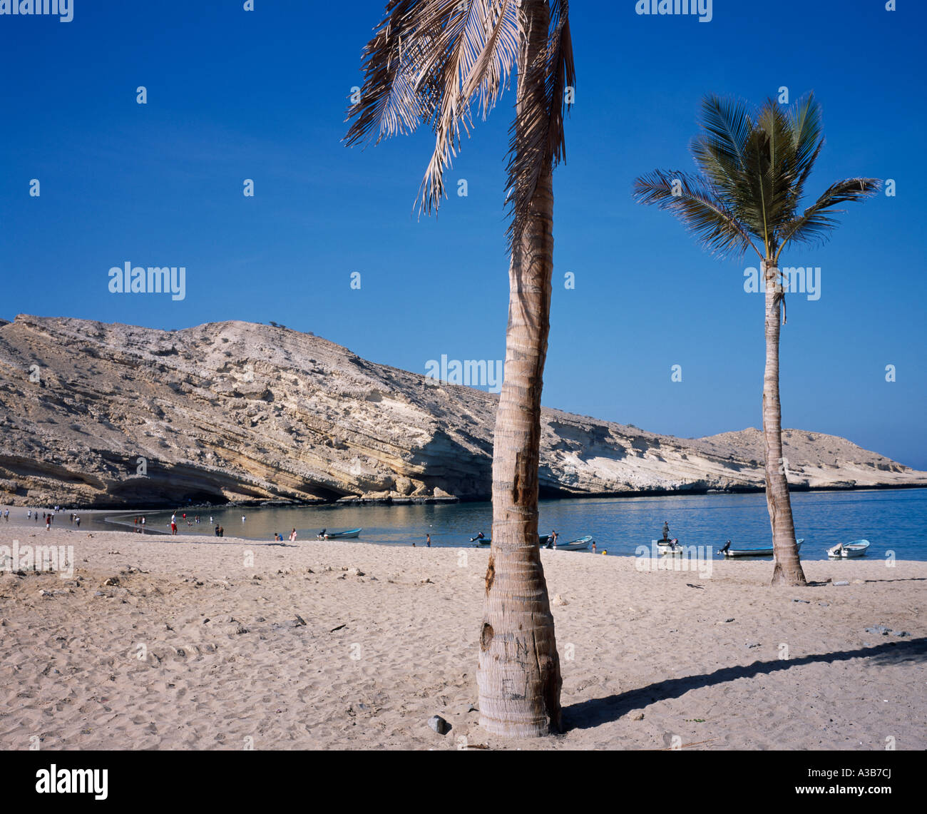 OMAN Middle East Muscat Bandar Jissah beach near Al Bustan Hotel outside capital city People at water's edge beside eroded rocks Stock Photo