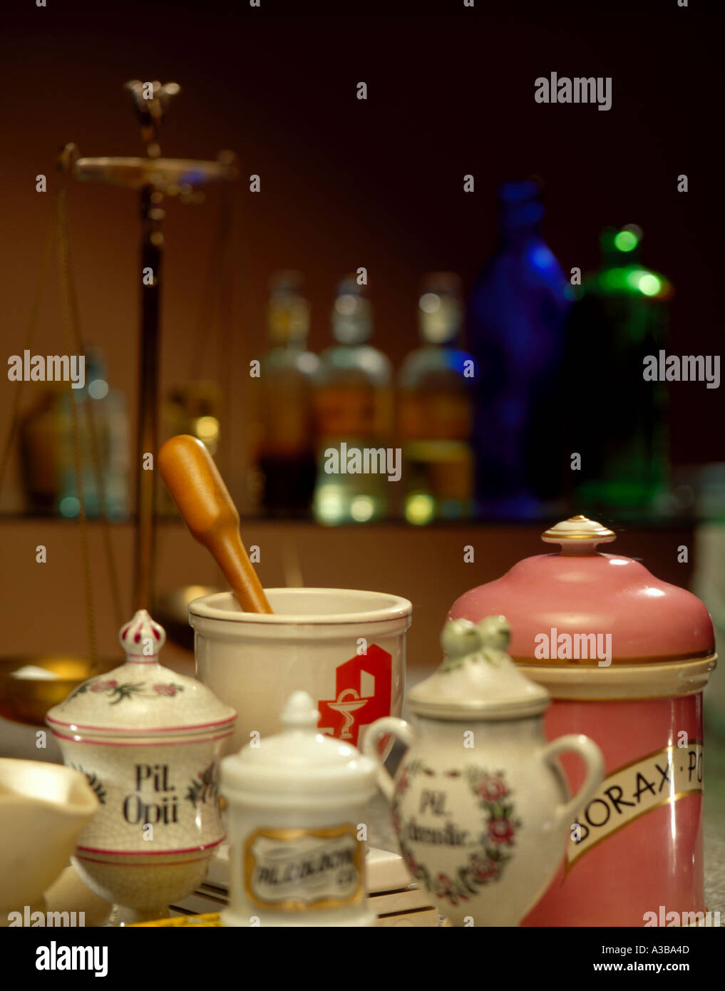 Chemist pots, mortar and pestle, circa 1920 with medicinal bottles out of focus behind Stock