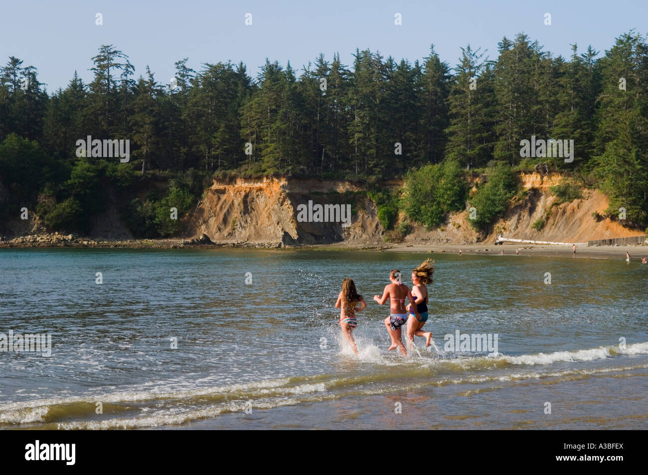 Group of teenage girls running into the water on the beach at Sunset ...