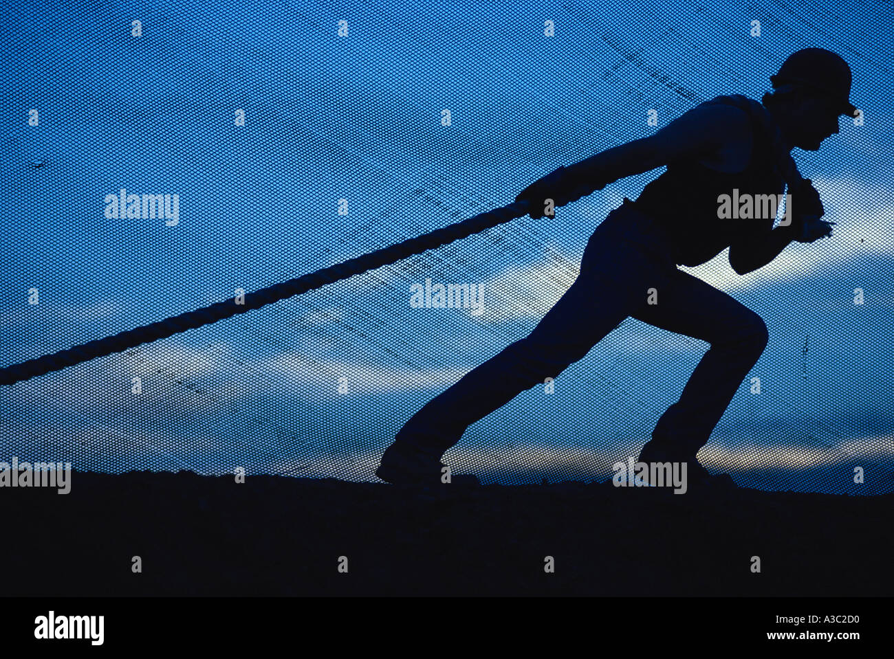 Worker Puling Rope Silhouette of a construction worker pulling a rope behind a mesh fence ...