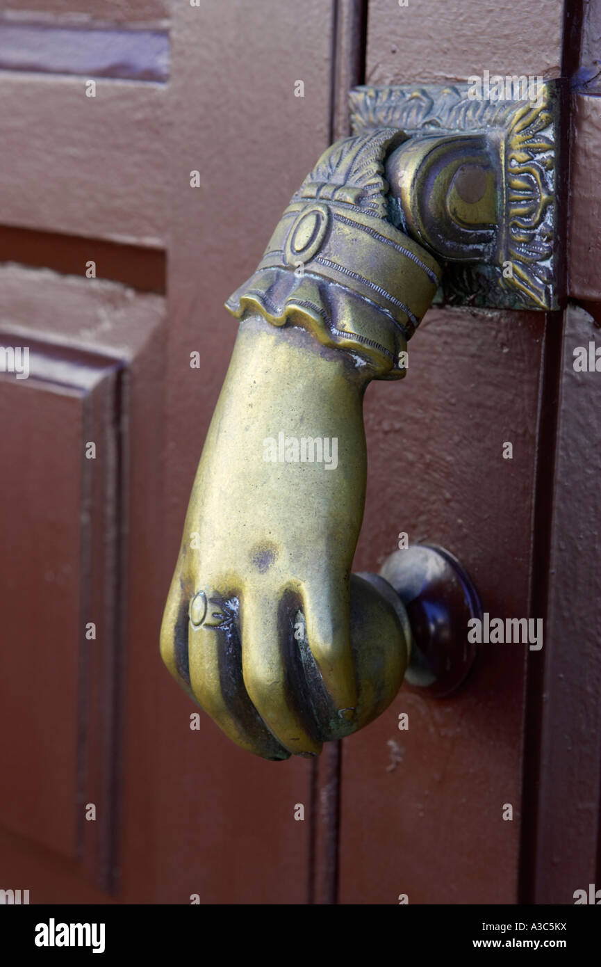 traditional antique brass hand and ball door knocker on wooden door