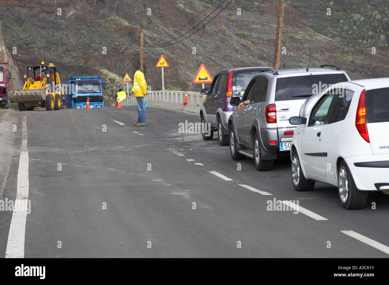 spanish road worker looks at road works on coastal cliff road to give the go signal on Tenerife Canary Islands Spain Stock Photo