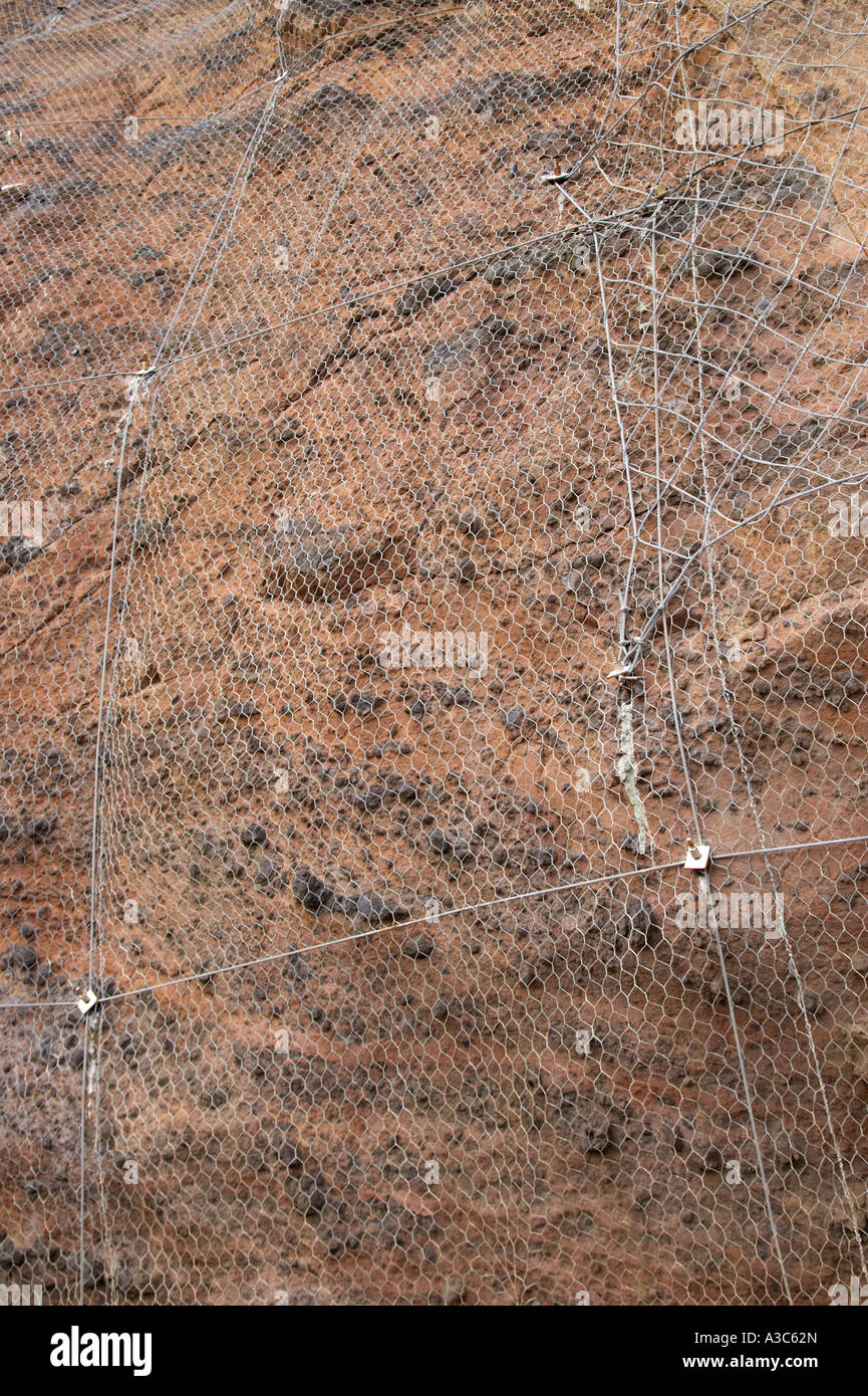 mesh wire cage attached to rocky cliff face to stop rocks falling onto