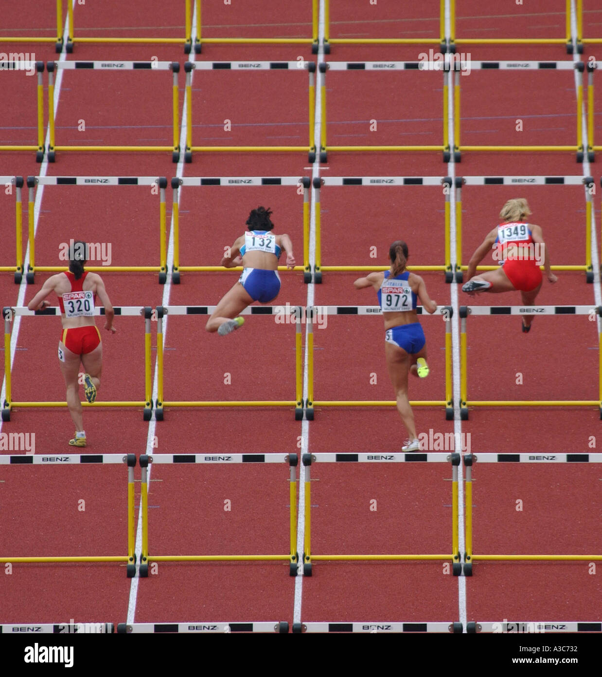 female runners jumping the obstacle of a 100m hurdles race at the